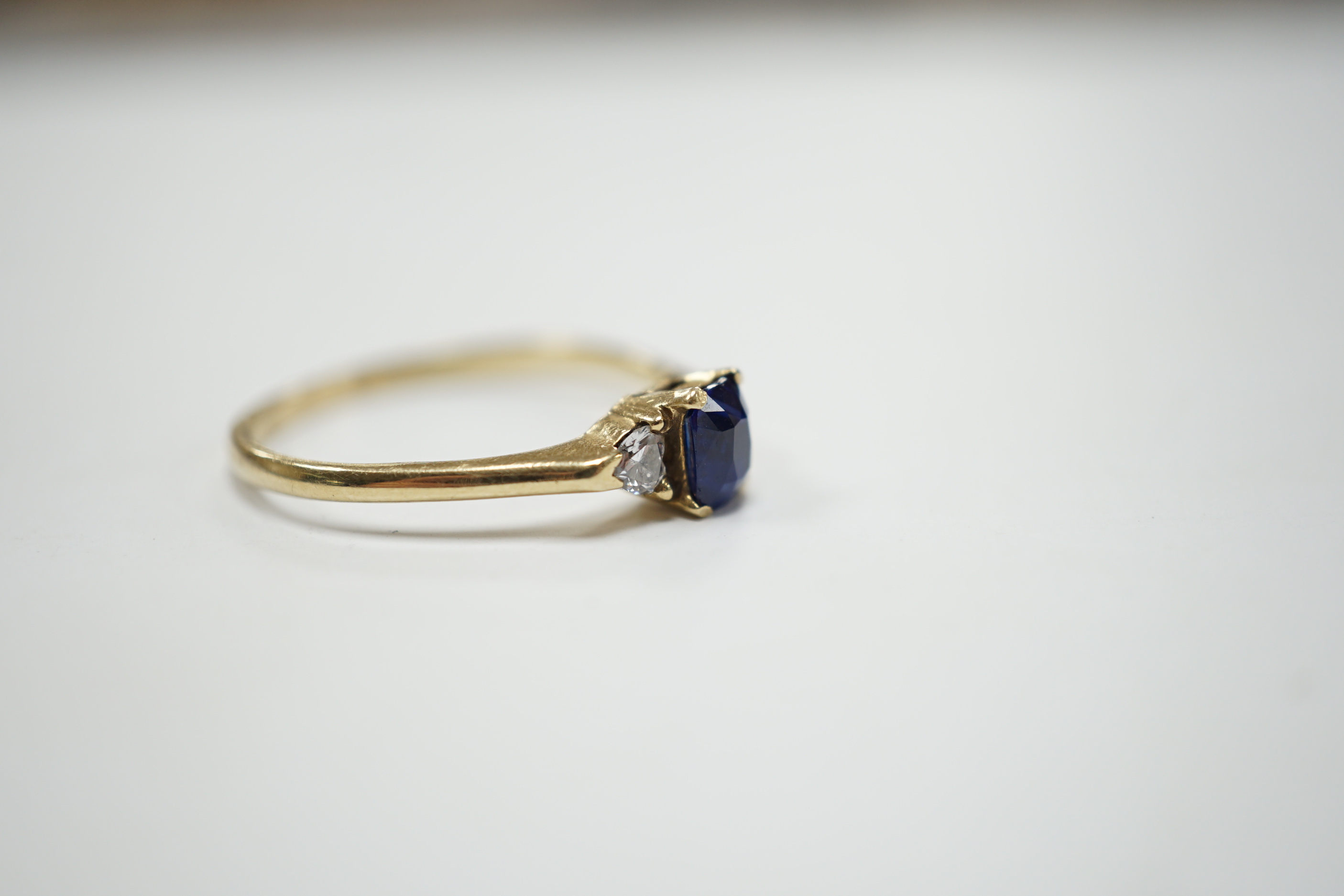 A yellow metal and single stone oval cut sapphire set ring, with two stone heart shaped diamond set shoulders, size U/V, gross weight 2.4 grams.